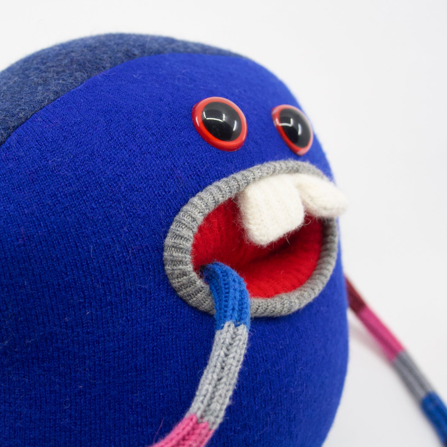 blue stuffed cute monster plush with red eyes and pocket mouth